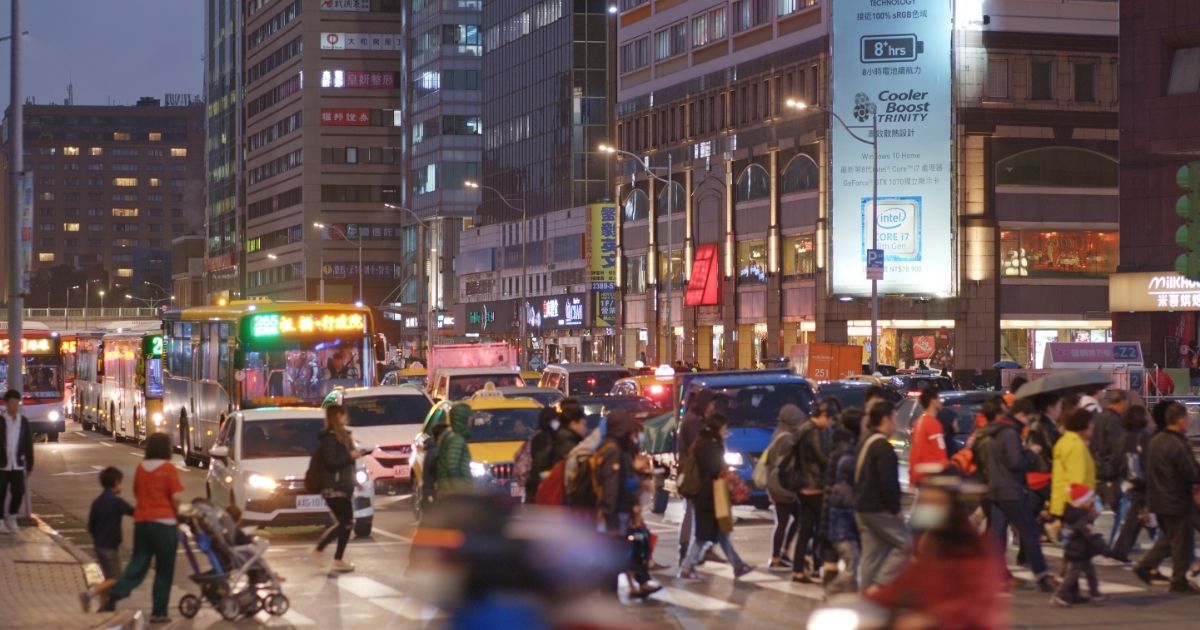 台北市中心部の夜の街並み。多くの人や車が行き交う交差点の様子。